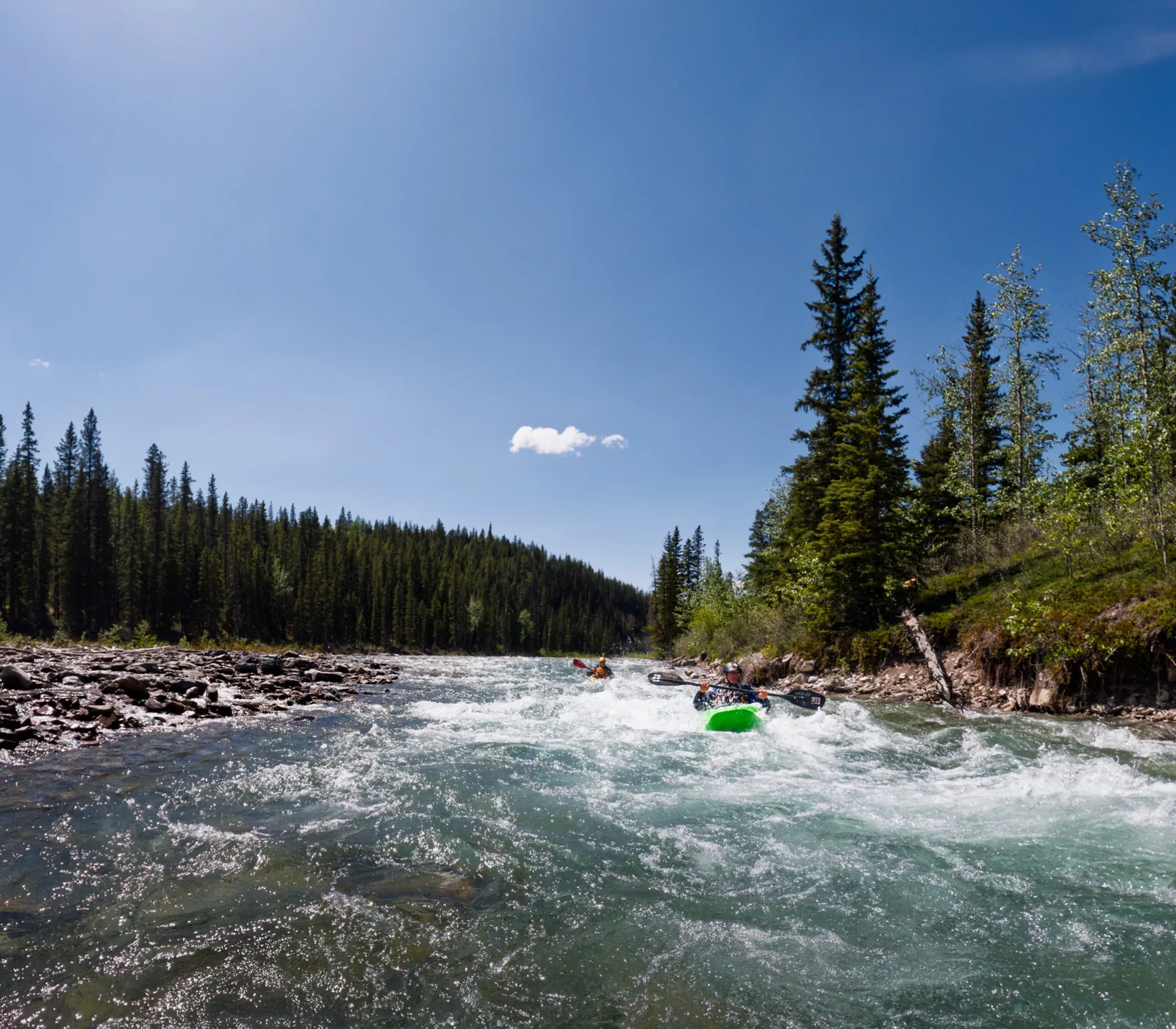 Airdrie Kayak Club paddlers running whitewater on a sunny Southern Alberta river
