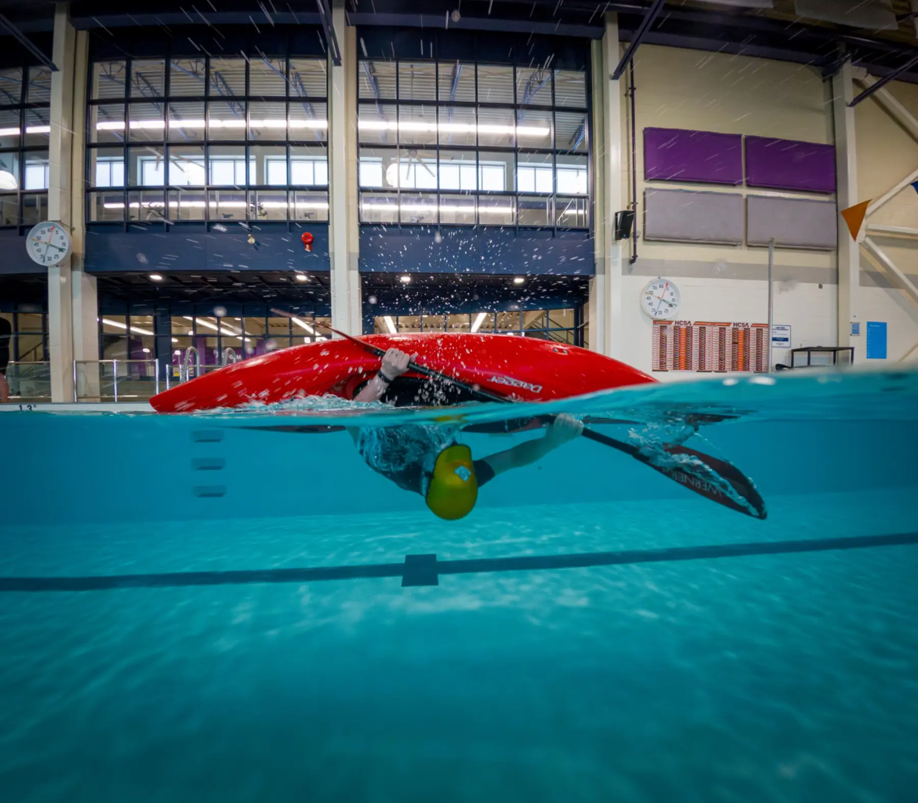 A kayaker practising a roll photographed above and below the pool surface